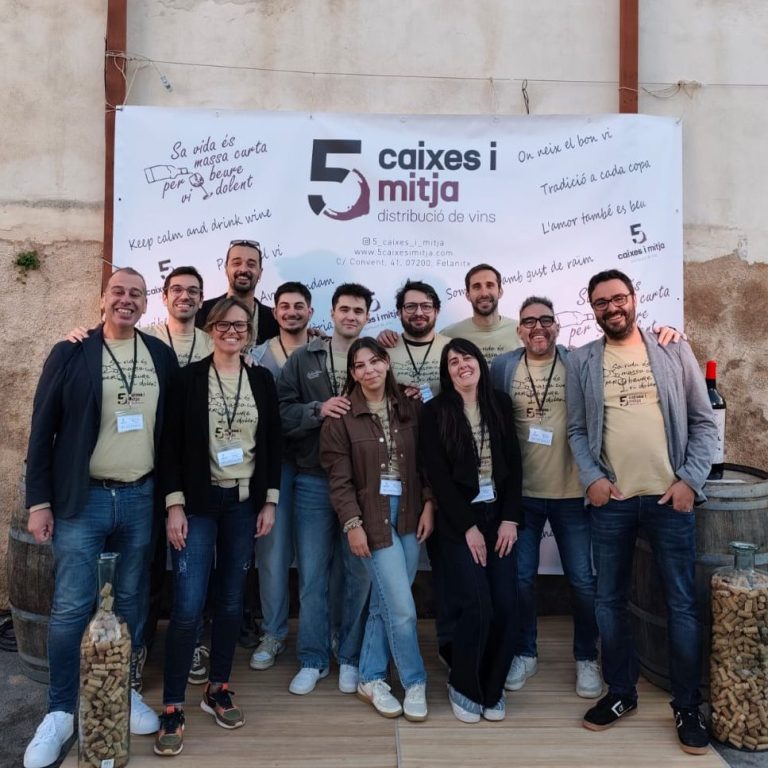 Grupo de personas sonrientes posando frente a un banner de un evento.